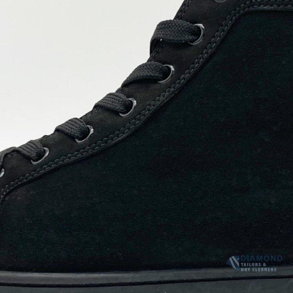 The same Louboutin sneaker after cleaning — the suede restored to a deep, even black
