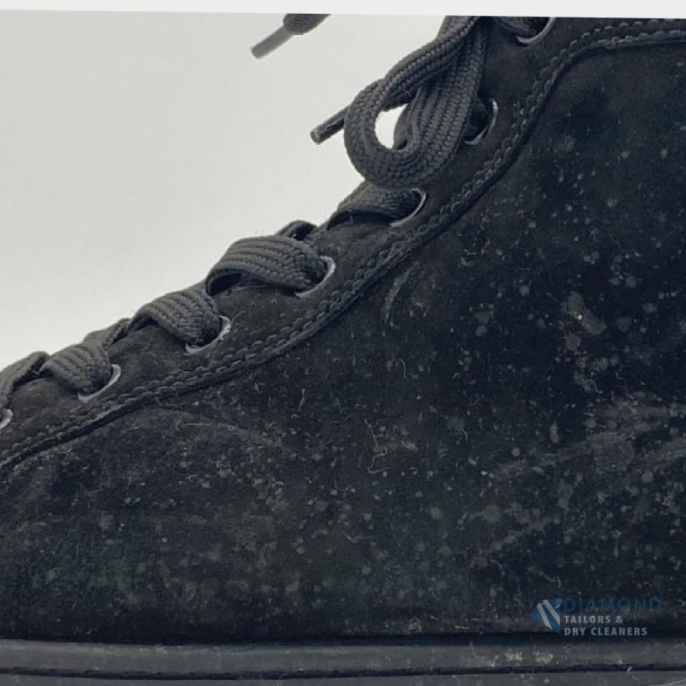 Black suede Christian Louboutin high-top sneaker before cleaning — the suede is dull, greyed and covered in lint